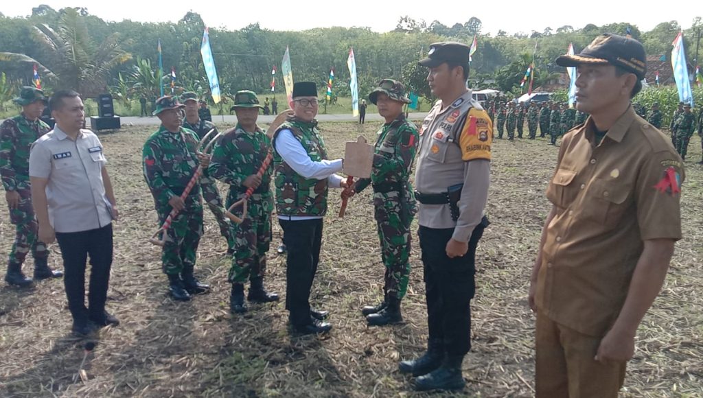 Pj Bupati OKU H Teddy Meilwansyah SSTP MM MPd menyerahkan alat kerja kepada perwakilan personal Satgas V TMMD KE-117 di Desa Karang Endah Kecamatan Lengkiti Kabupaten OKU. Foto Kanalberita.id / Apriansyah