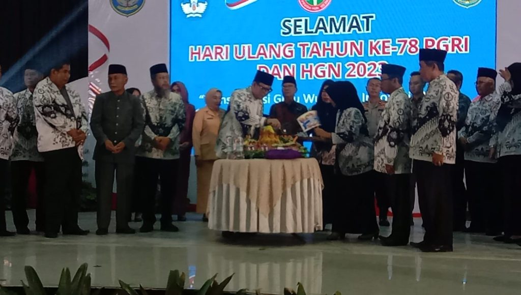 PJ Bupati OKU H Teddy Meilwansyah SSTP MM MPd memoteng nasi tumpeng pada HUT PGRI ke-78 dan HGN tahun 2023 di gedung Kesenian Baturaja sabtu (15/11/2023). Kanalberita.id / Apriansyah