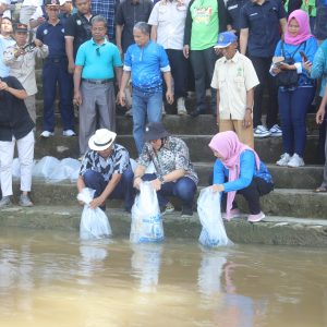 Penjabat Bupati OKU H Teddy Meilwansyah SSTP MM MPd bersama Kepala Dinas Perikanan OKU Ir Hj Tri Aprianingsih menebar bibit ikan di periaran Sungai OKU. Kanalberita.id / Edo